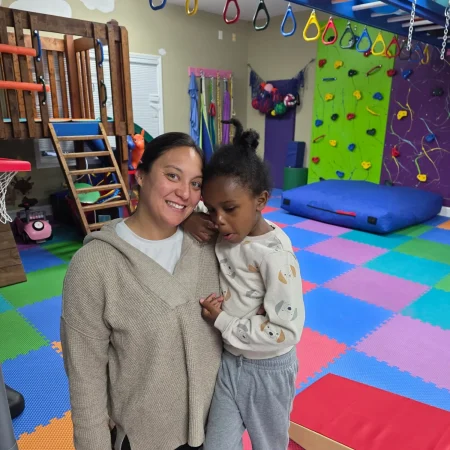 Therapist holding a child in a colorful pediatric therapy gym