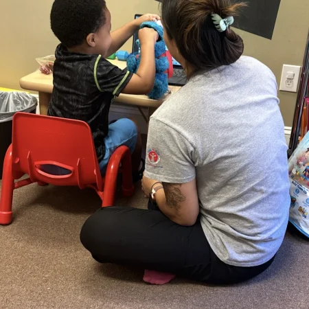 Therapist supporting a child during a seated play activity