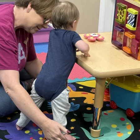 Therapist supporting a toddler standing during a therapy activity