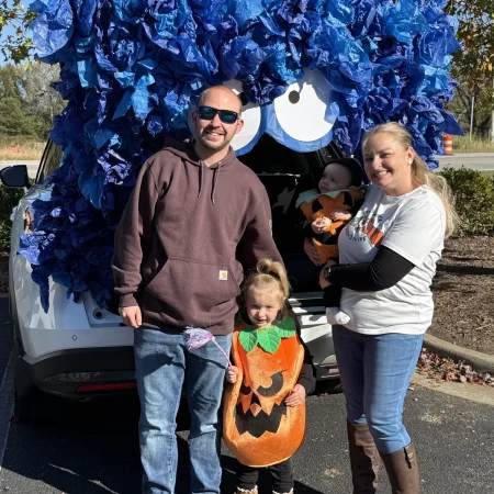 Family posing at a Halloween trunk-or-treat display