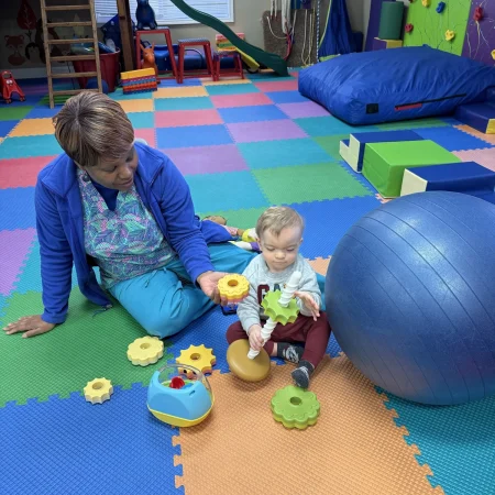 Therapist helping a toddler play with interlocking gears