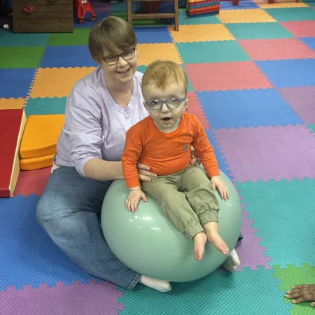 Therapist supporting a child seated on a therapy ball