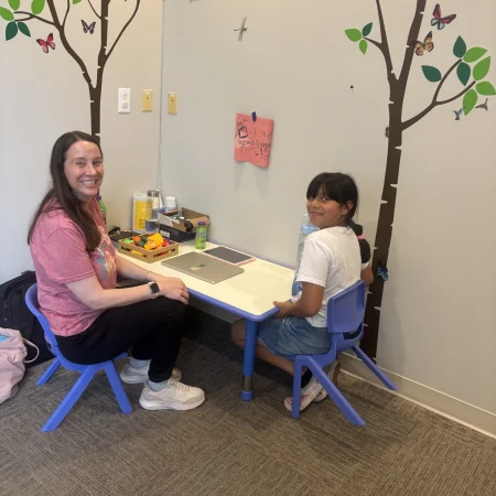 Therapist and child seated together at a child-sized activity table
