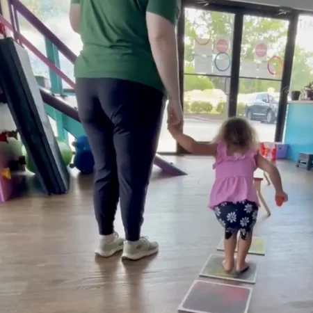 Therapist guiding a child along a colorful sensory path