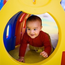Baby crawling through a bright play tunnel