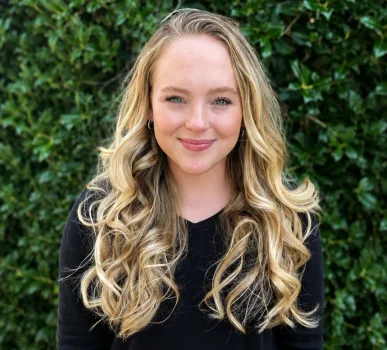 Katelyn Overcash smiling in front of a hedge