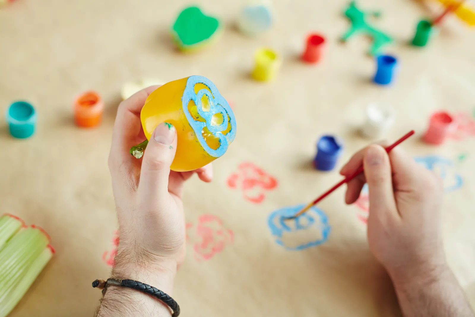 Person using a cut bell pepper and paintbrush for a food art activity