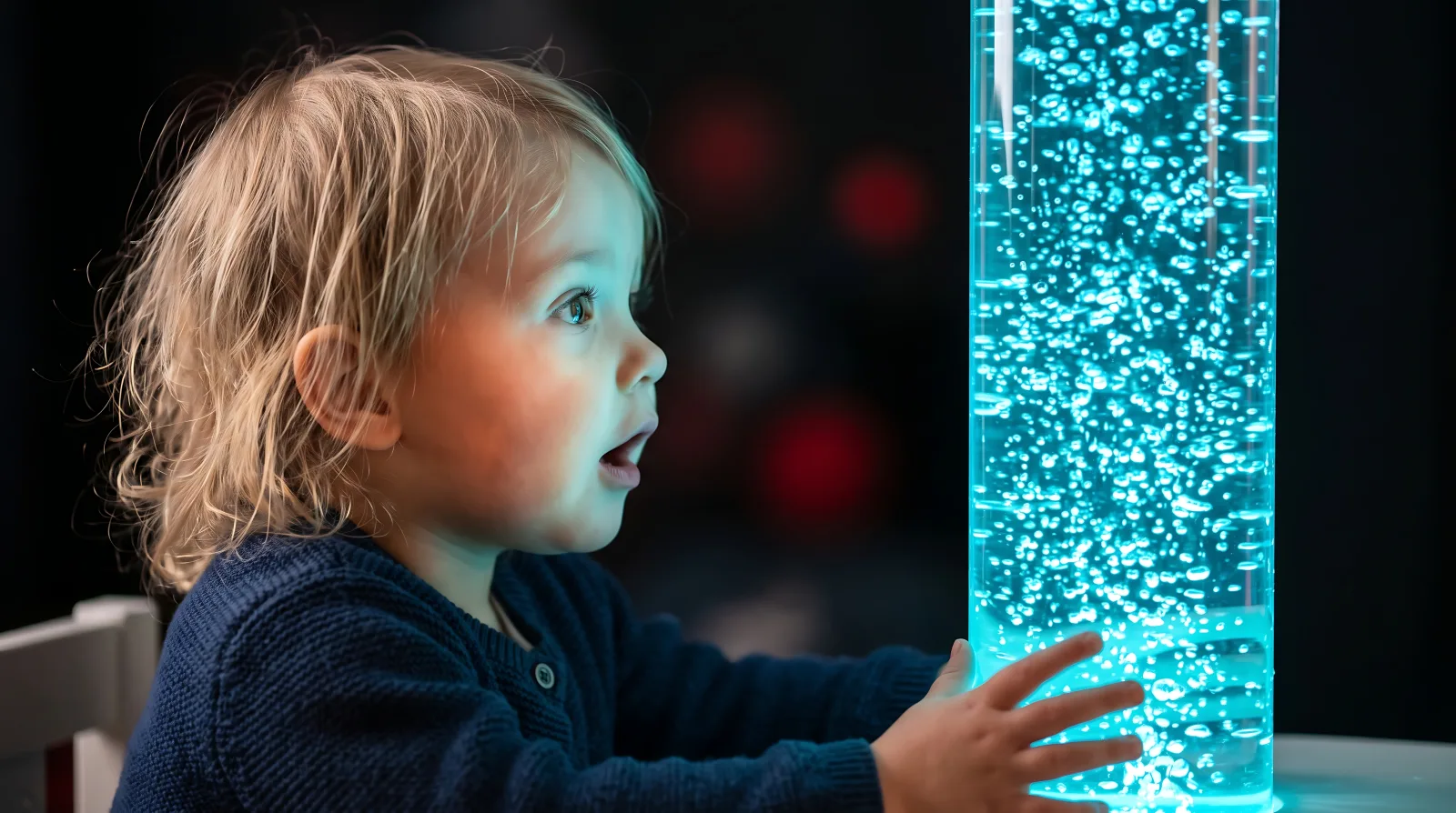 Child exploring a glowing blue bubble tube